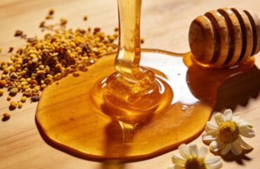 A close-up image of thick, golden Natural Honey flowing over a wooden surface, highlighting the honey health benefits and its superfood quality.